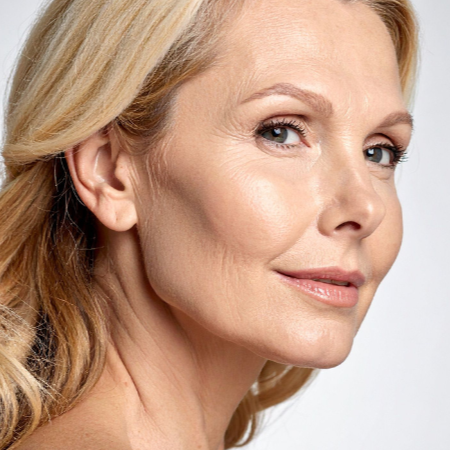 Close-up of a woman's face with a neutral expression on a light gray background